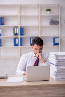 Young employee and too much work at workplace