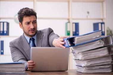 Young employee and too much work at workplace