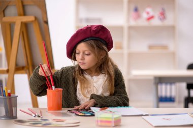 Küçük kız evde resim yapmaktan zevk alıyor.