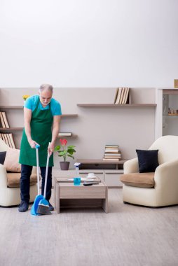 Yaşlı müteahhit evi temizliyor.