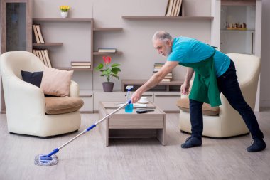 Yaşlı müteahhit evi temizliyor.