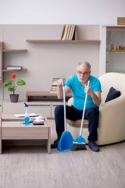 Yaşlı müteahhit evi temizliyor.