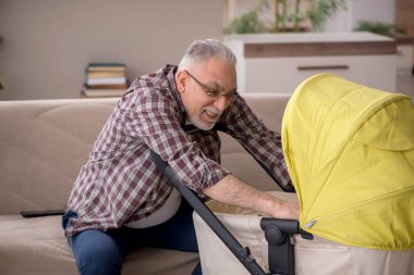 Old man looking after baby at home