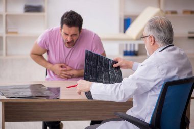 Genç hasta yaşlı doktoru ziyaret ediyor.