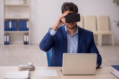 Genç çalışanın iş yerinde sanal gözlüklerle eğlenmesi