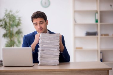 Young employee and too much work at workplace