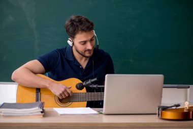 Sınıfta oturan genç müzik öğretmeni.