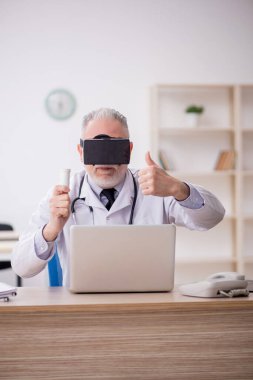 Old doctor wearing virtual glasses at the hospital