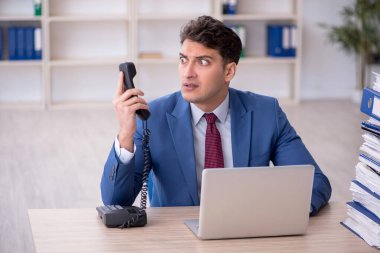 Young employee and too much work at workplace