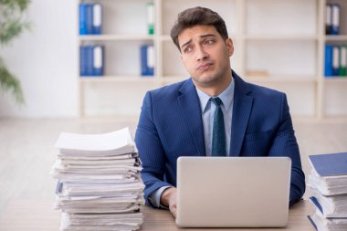 Young employee and too much work at workplace