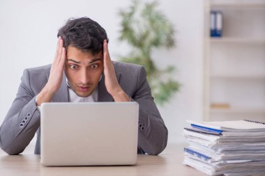 Young employee and too much work at workplace