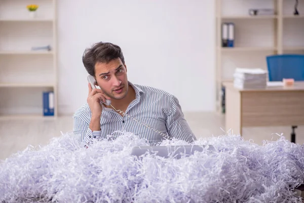 Young businessman employee and a lot of cut papers at workplace
