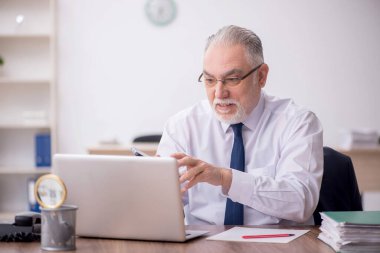 Old employee sitting at workplace