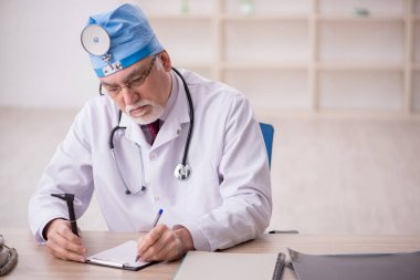 Old doctor otorhinolaryngologist working in the clinic