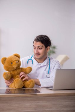 Genç doktor oyuncak ayı tutuyor.