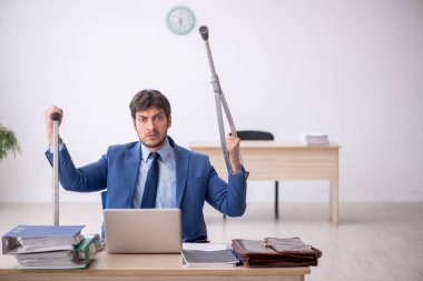 Young employee after car accident sitting at workplace