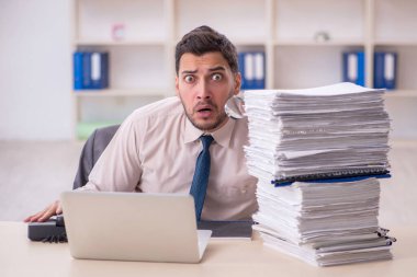 Young employee and too much work at workplace
