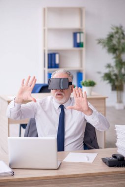 Old businessman employee wearing virtual glasses in the office