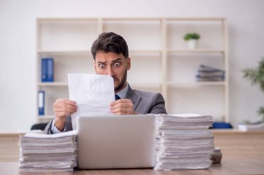 Young employee and too much work at workplace