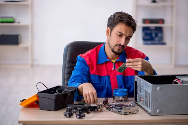 若い修理工はワークショップでコンピュータを修理する — ストック写真