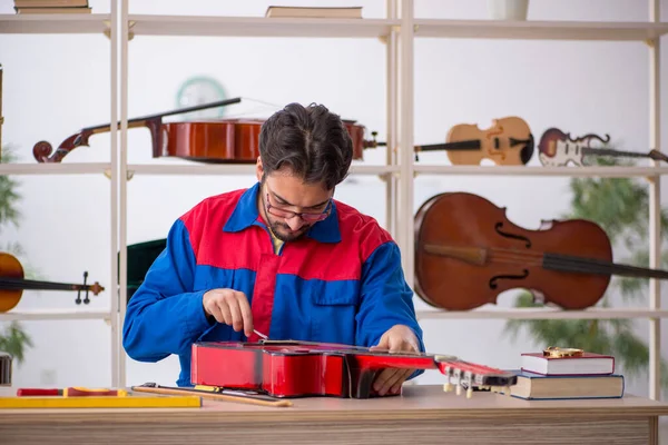 Ung Man Som Reparerar Musikinstrument Inomhus — Stockfoto