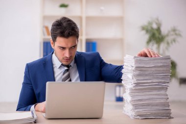 Young employee and too much work at workplace