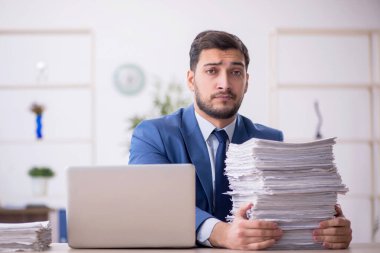 Genç bir çalışan ve ofiste çok fazla iş var.