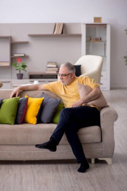 Evde bir sürü yastığı olan yaşlı bir adam.