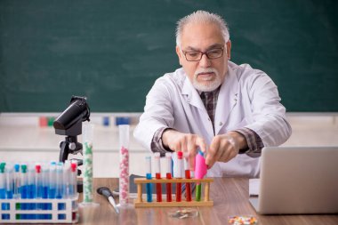 Old teacher chemist sitting in the classroom