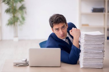 Young employee and too much work at workplace