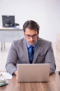 Genç işadamı işyerinde oturuyor.