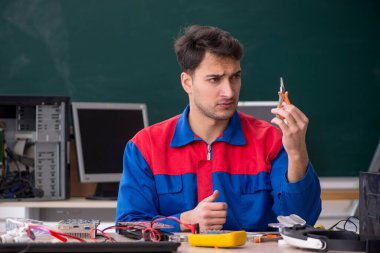 Sınıfta bilgisayar tamir eden genç bir tamirci.