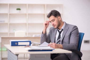 Genç işadamı işyerinde oturuyor.