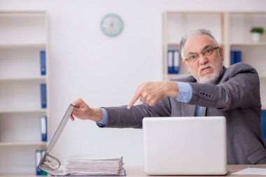 Old employee sitting at workplace