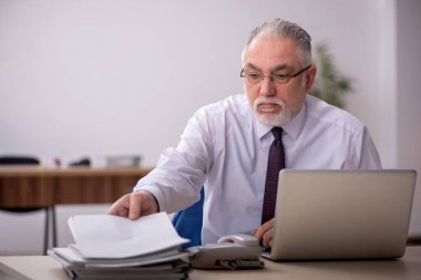 Old employee sitting at workplace