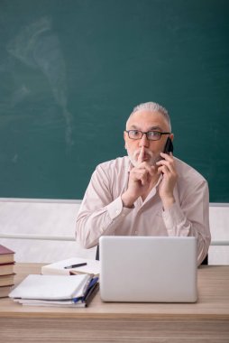 Old teacher sitting in the classroom