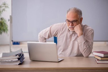 Eski öğretmen beyaz tahtanın önünde.