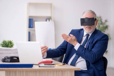 Old businessman employee wearing virtual glasses in the office