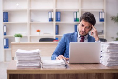 Young employee and too much work at workplace