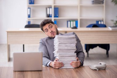 Young employee and too much work at workplace