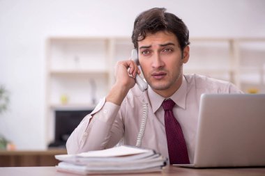 Genç işadamı ve işyerinde çok fazla iş var.