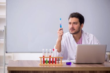 Young chemistry teacher sitting in the classroom