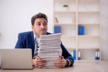 Young employee and too much work at workplace