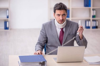 Young employee after car accident sitting at workplace