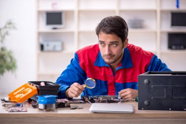 Atölyede bilgisayar tamir eden genç bir tamirci.