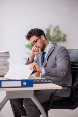 Young employee and too much work at workplace