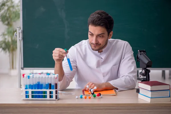 教室に座っている若い化学者の先生 — ストック写真