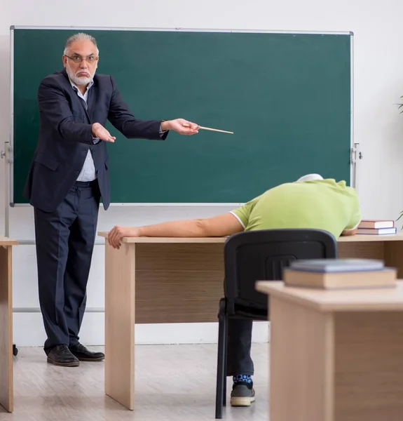 Aged male teacher and lazy student in the classroom