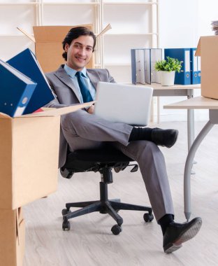 The young man employee with boxes in the office