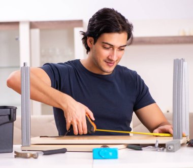 Evde mobilya tamir eden genç adam.